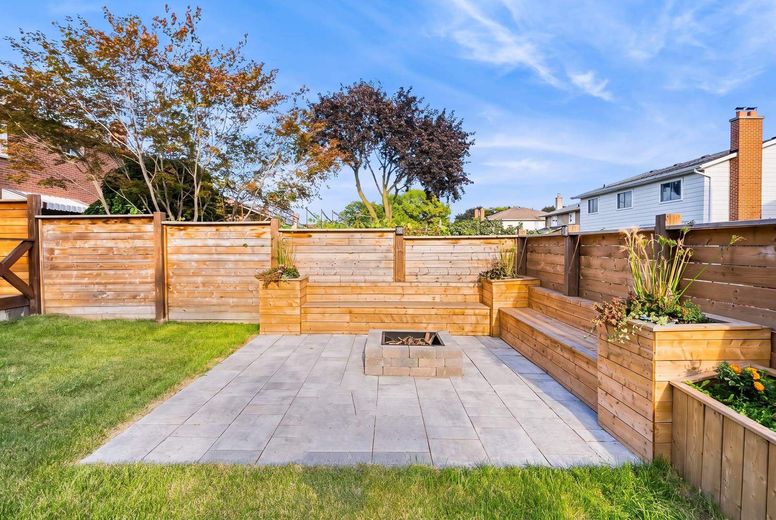 Renovated backyard with paver patio, masonry fire pit, cedar benches and planter walls