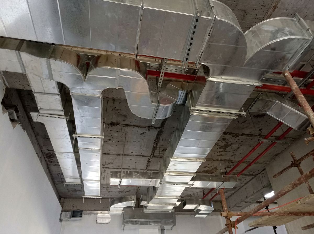 Precision elbow transitions and sealed joints in exposed rectangular ductwork on a concrete ceiling